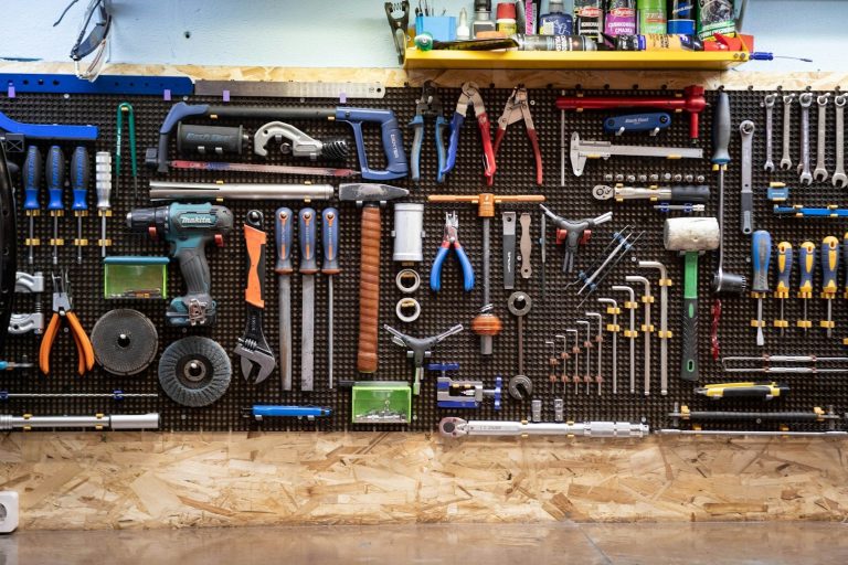 A wall-mounted tool organiser displaying various hand tools and power tools.
