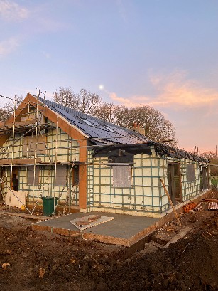 Construction site showing wooden framework and scaffolding for a house.