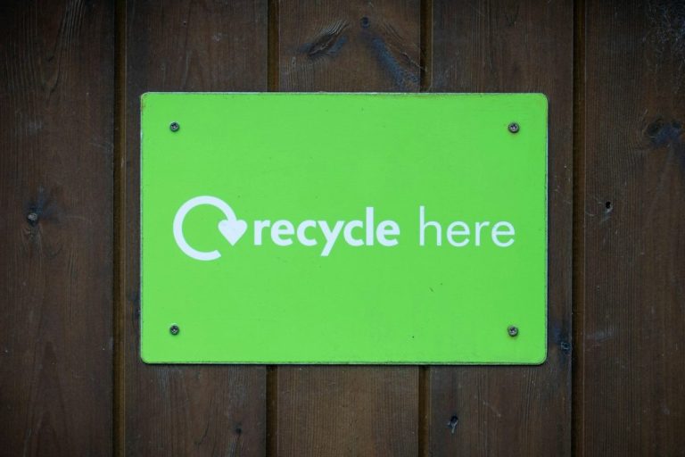 Green sign with white text stating "recycle here."