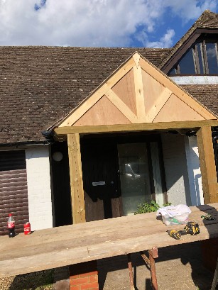 Front of a house with a constructed gable and wooden structure.