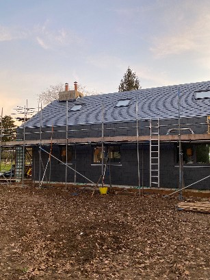 Construction site showing wooden framework and scaffolding for a house.