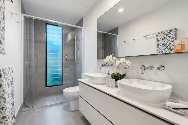 Modern bathroom featuring two basin sinks, a shower, and stylish décor.