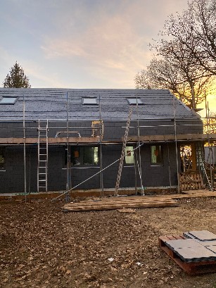 Construction site showing wooden framework and scaffolding for a house.