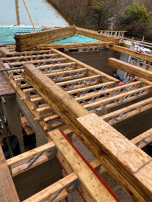 Construction site showing wooden framework and scaffolding for a house.